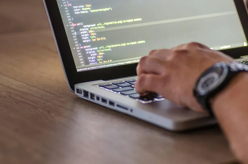 Hands on a laptop with code on the screen